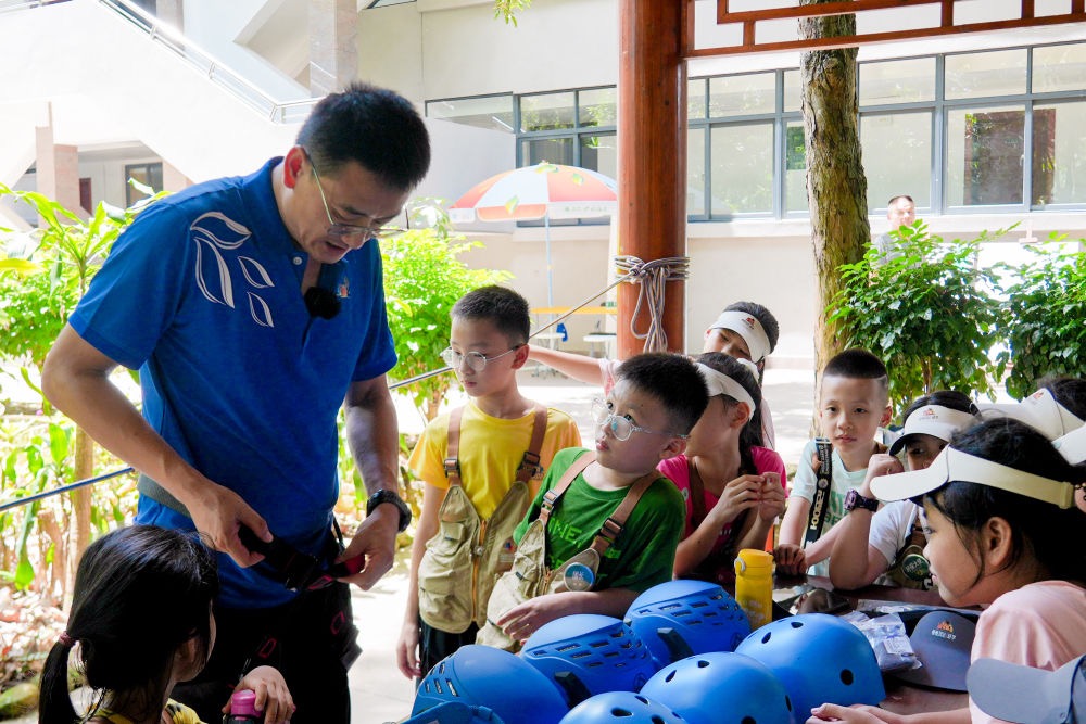 A staff member is demonstrating to children how to properly wear climbing suits for climbing cocoa trees. /Courtesy of Xinglong Tropical Botanical Garden