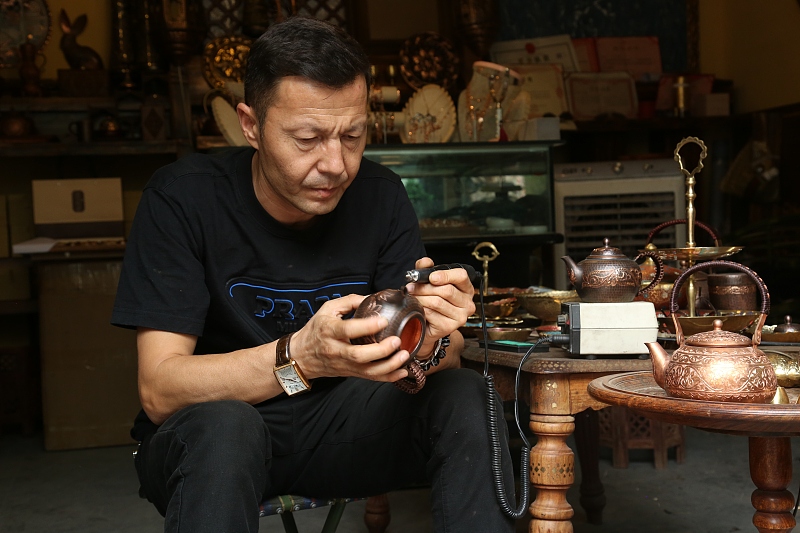 A photo taken on August 28, 2023 shows a craftsman making copperware in Kuqa of Aksu Prefecture in Xinjiang. /CFP