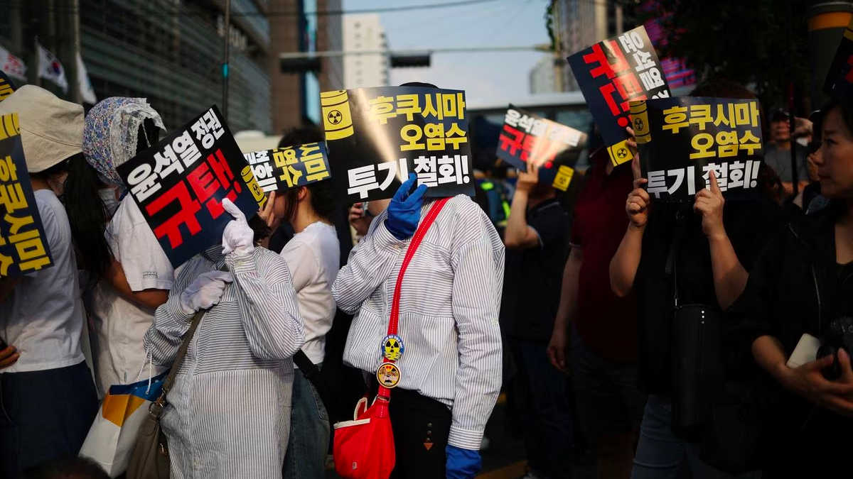 South Korean people take shade with signs during a protest against Japan's discharge of radioactive water from the wrecked Fukushima nuclear power plant into the Pacific Ocean, in Seoul, South Korea, August 26, 2023. /Reuters