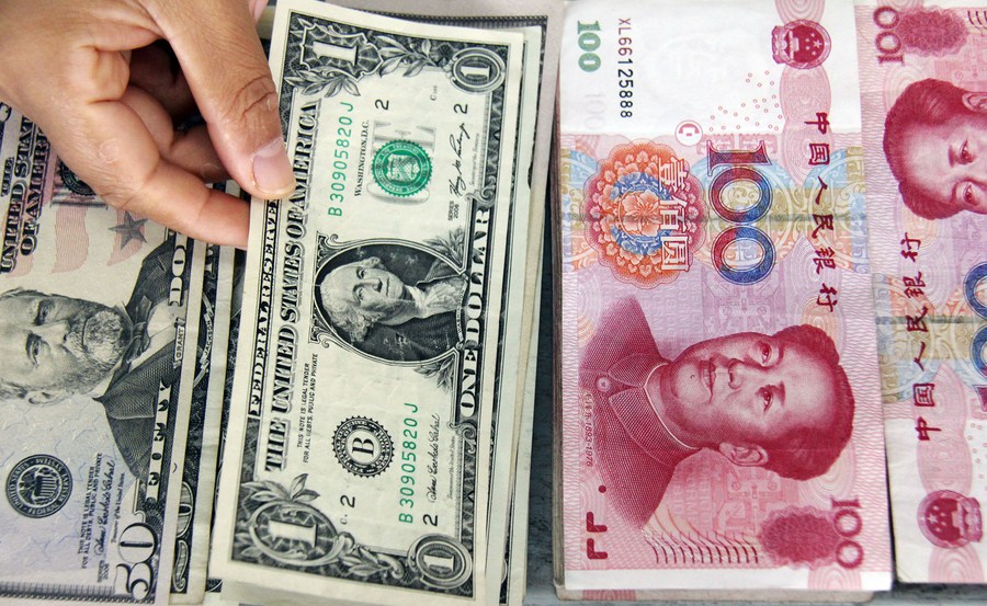 File photo shows a teller picks a dollar bill among banknotes of U.S. dollar and Renminbi (RMB) at a bank in Linyi, east China's Shandong Province. /Xinhua