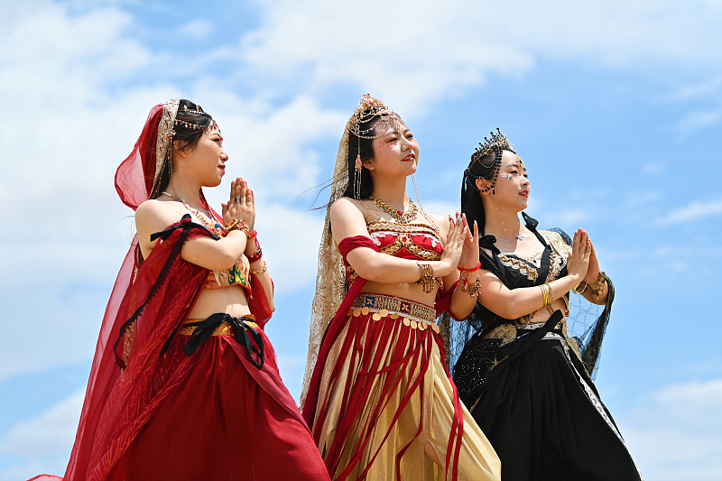 Tourists dressed in traditional costumes pose for photos at the Mingsha Mountain Crescent Spring scenic spot in Dunhuang City, Gansu Province, July 21, 2023. /CFP