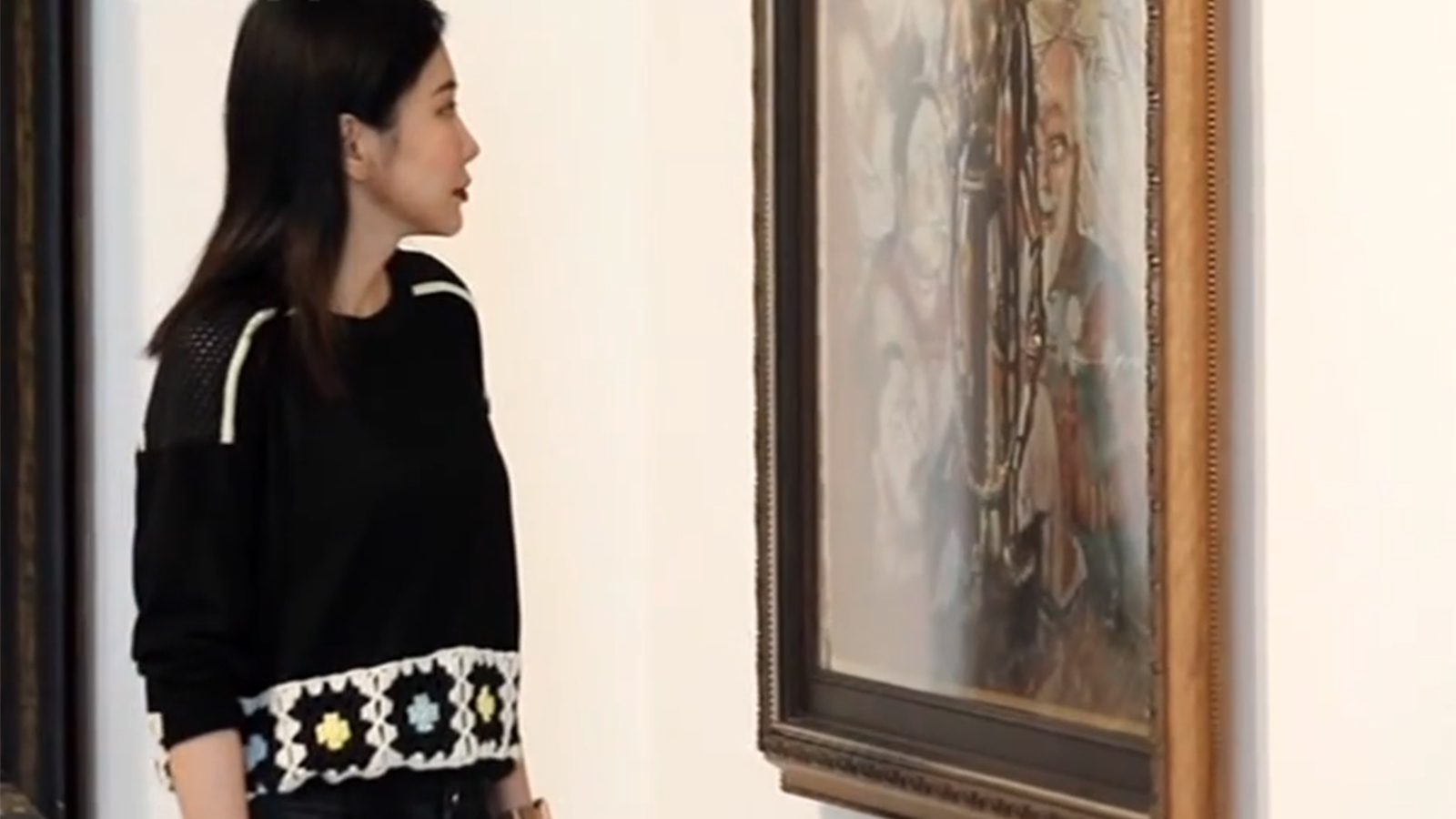 Mi Qiaoming looks at one of her paintings at an exhibition. /CGTN