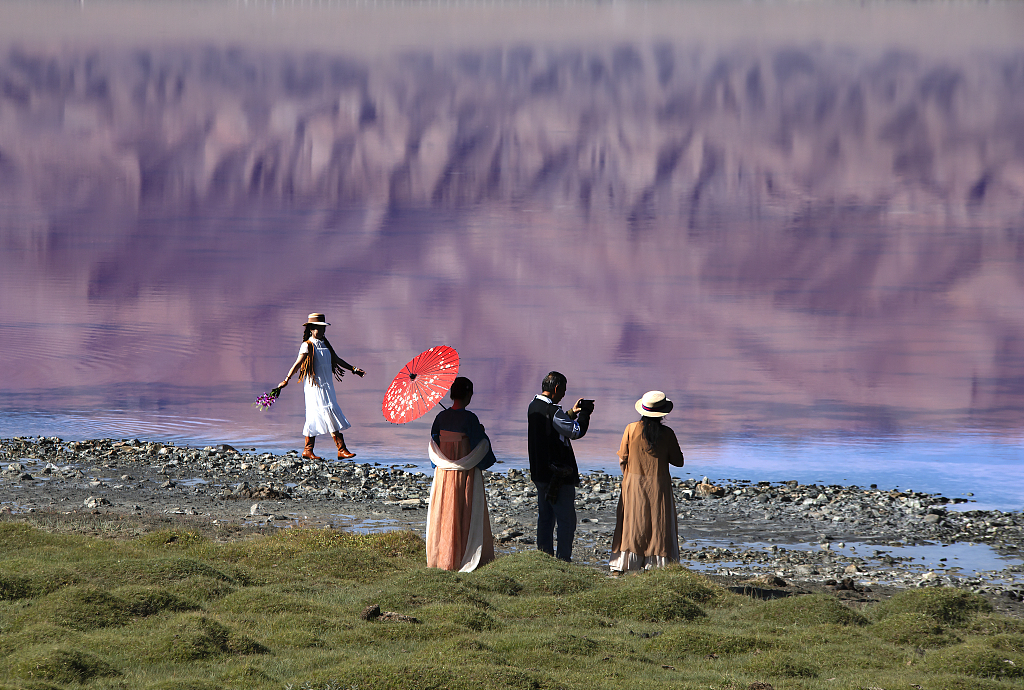 A photo taken on August 27, 2023 shows visitors standing on the shoreline of Tuolekule Lake, appreciating the pink natural wonders in Hami, Xinjiang. /CFP