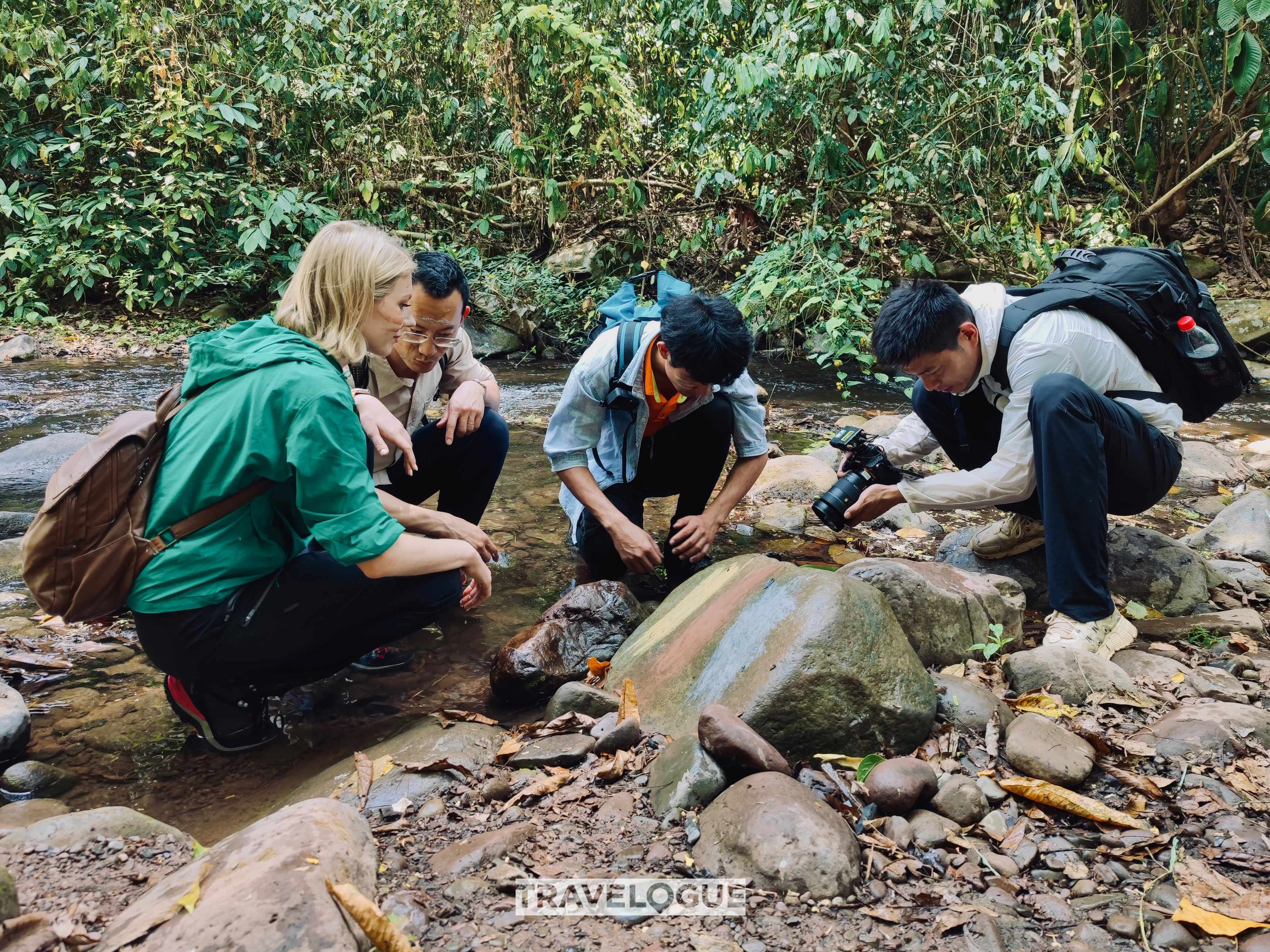 CGTN reporters try to use rocks to protect their skin in the rainforests of Xishuangbanna, Yunnan Province. /CGTN