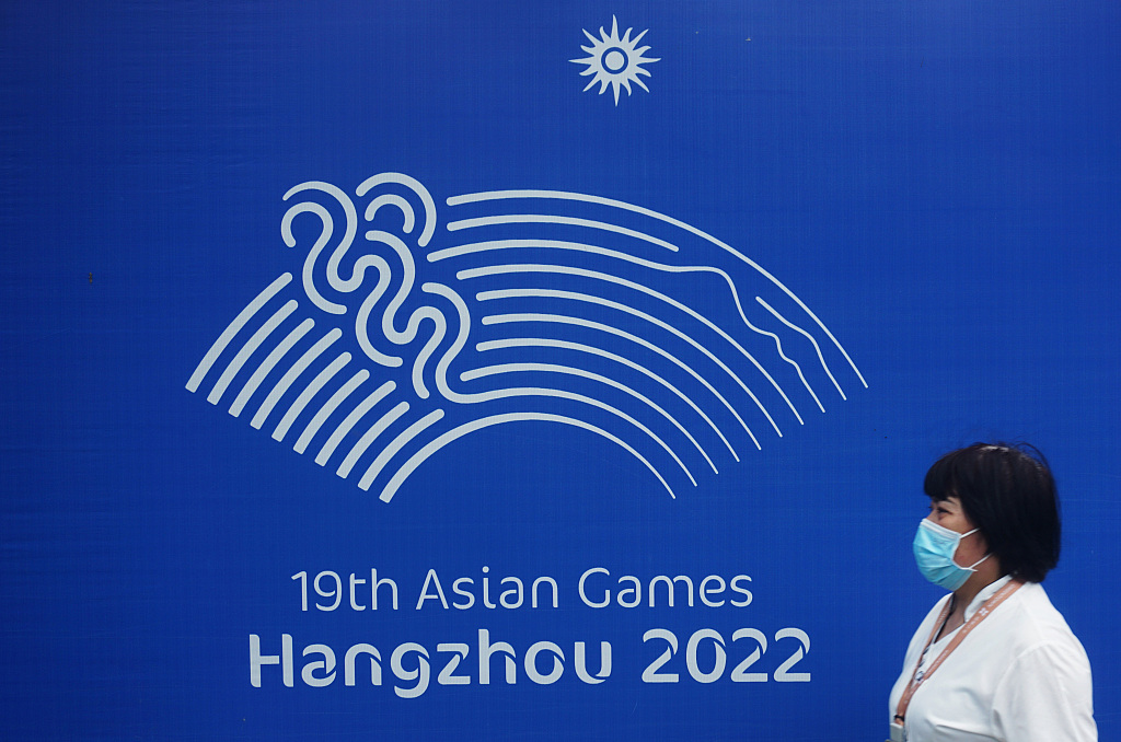 A woman passes by a display of the emblem of the 19th Asian Games in Hangzhou, Zhejiang. /CFP