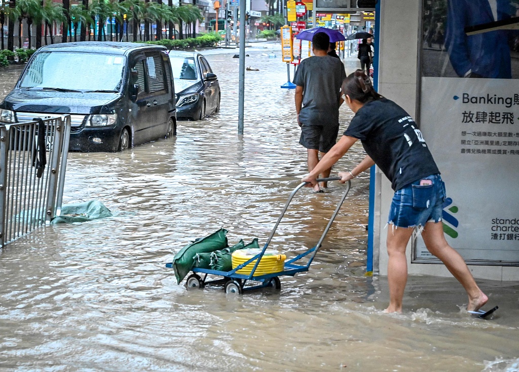 A woman pushes a cart on a flooded road in Hong Kong SAR, China, September 8, 2023. /CFP