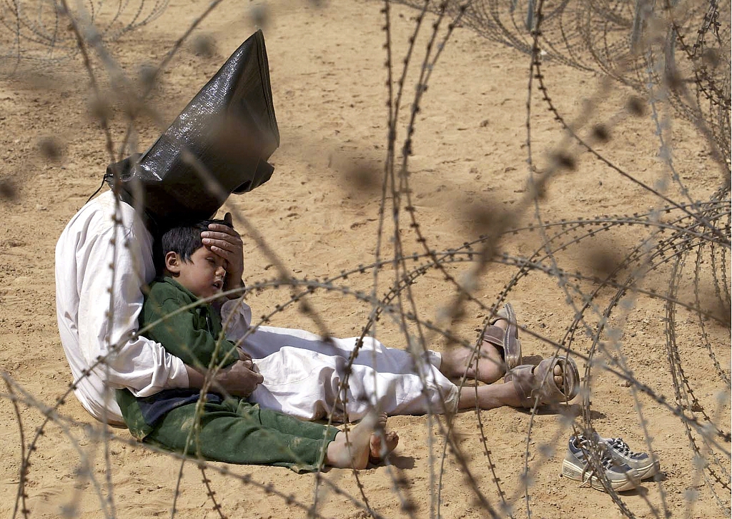 An Iraqi prisoner of war (POW) comforts his son at a regroupment center for POWs near An Najaf, Iraq, March 31, 2003. /CFP