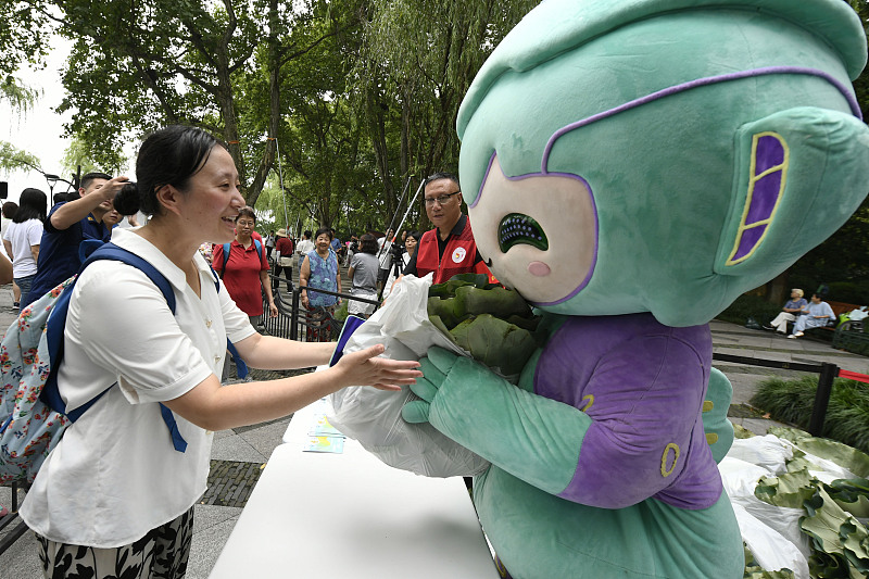 The mascot Lianlian of the 19th Asian Games interacts with a resident in Hangzhou City, Zhejiang Province. /CFP