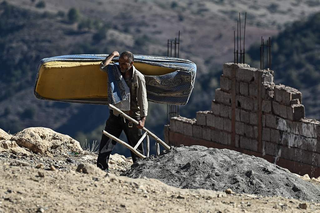 A man carries a mattress as he gathers belongings after his home was destroyed following an earthquake in the mountain village of Moulay Brahim in the central province of Al-Haouz, September 11, 2023. /CFP