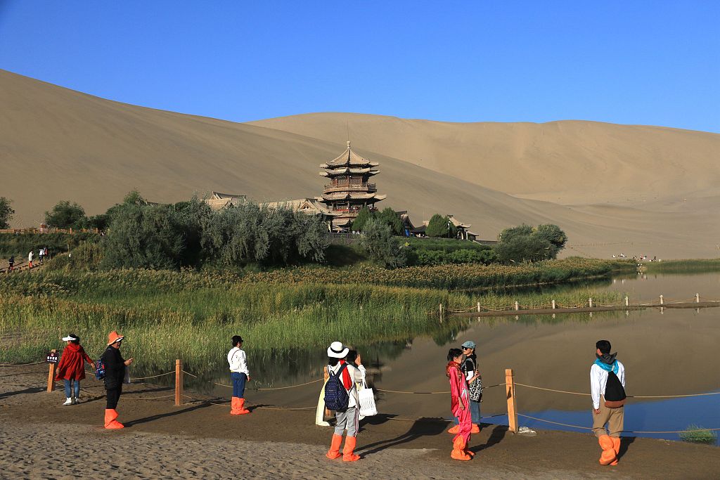 A photo taken on September 11, 2023, shows tourists visiting the Mingsha Mountain and Crescent Spring scenic spot in Dunhuang, Jiuquan, Gansu Province, China. /CFP