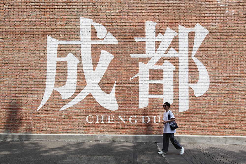 A visitor walks past a wall featuring the city's name at the Eastern Suburb Memory Fashion Industrial Park in Chengdu, Sichuan Province. /CGTN
