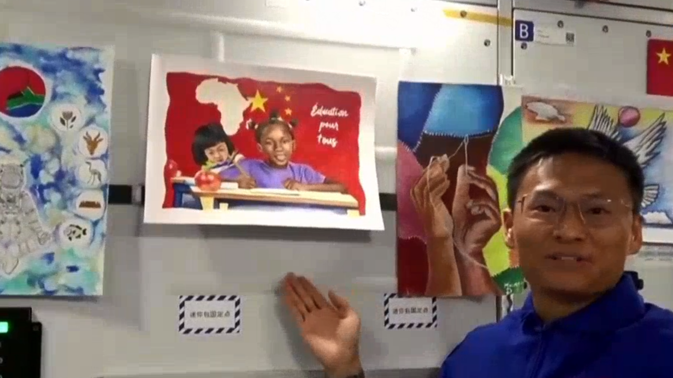Shenzhou-16 crew Gui Haichao introduces one of the paintings made by young African artists at the China Space Station, September 13, 2023. /CGTN