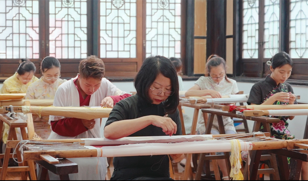 Meng Dezhi (center), a master of Sichuan embroidery, and her team, hand-embroider the certificates for the Golden Panda Awards. /Photo provided to CGTN