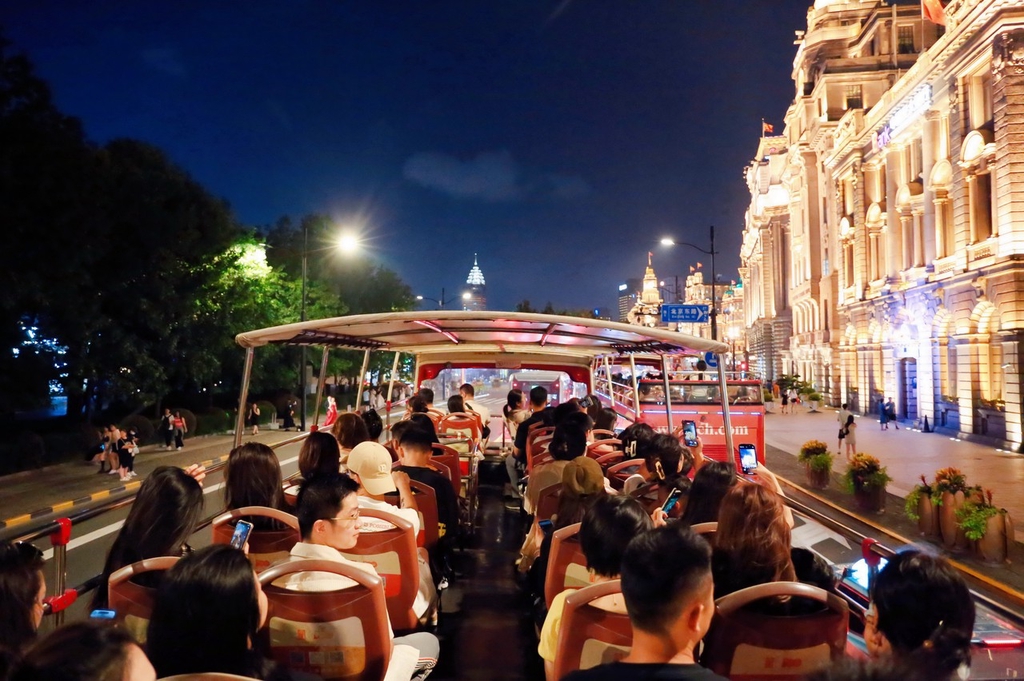 People enjoy an open-air bus tour on a convertible double-decker bus in the bustling Bund area of Shanghai, September 12, 2023. /IC