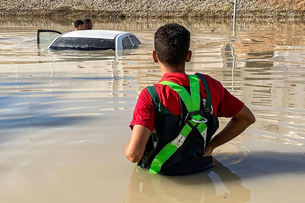 A member from Libyan Red Crescent standing in an inundated area near a submerged vehicle in the wake of floods after the Mediterranean storm 