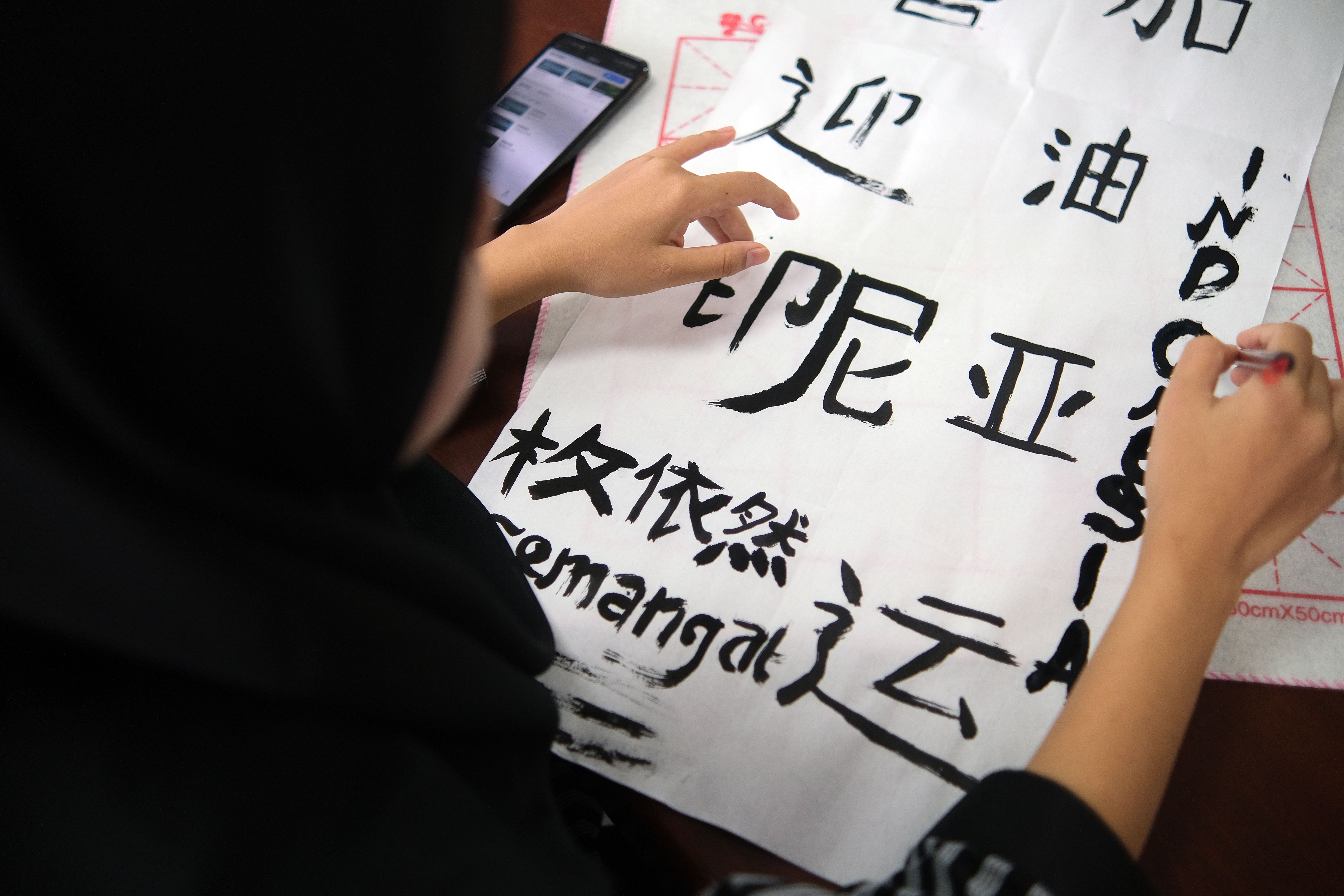 A photo taken on September 13, 2023 shows an international student working on her calligraphy piece as part of an Asian Games well-wishing activity held in Nantong, Jiangsu. /IC