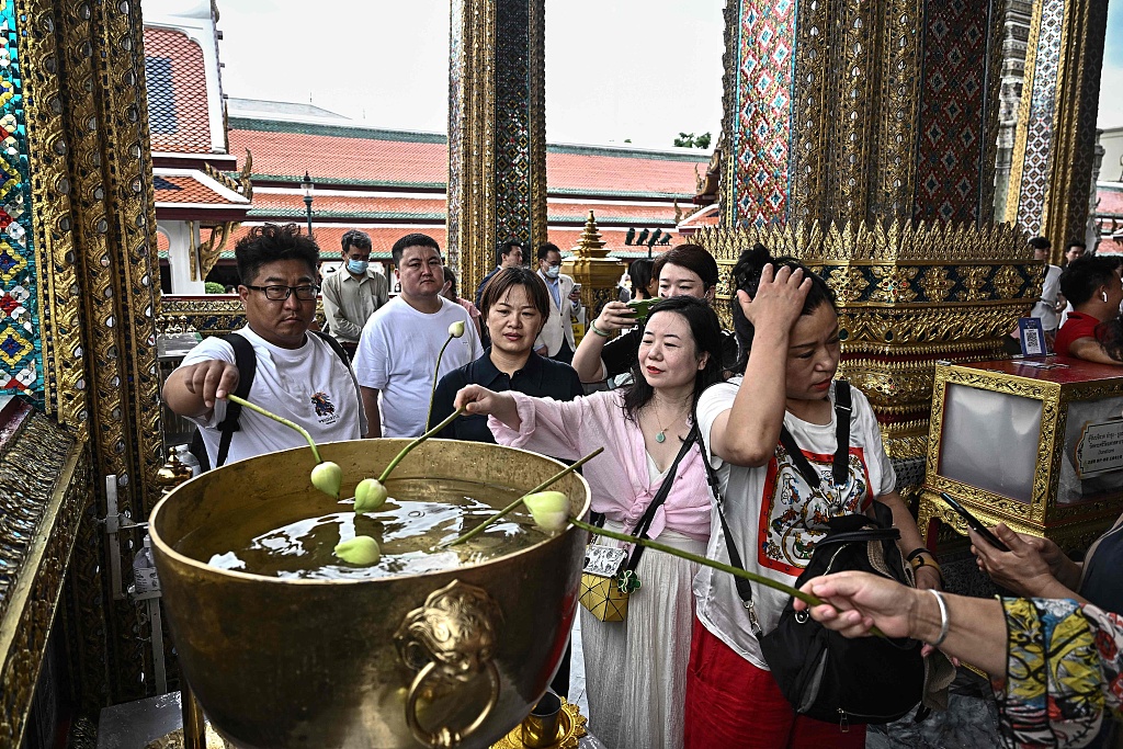 Chinese tourists dipping lotus bulbs in a water bowl at the Grand Palace in Bangkok, Thailand, September 10, 2023. /CFP