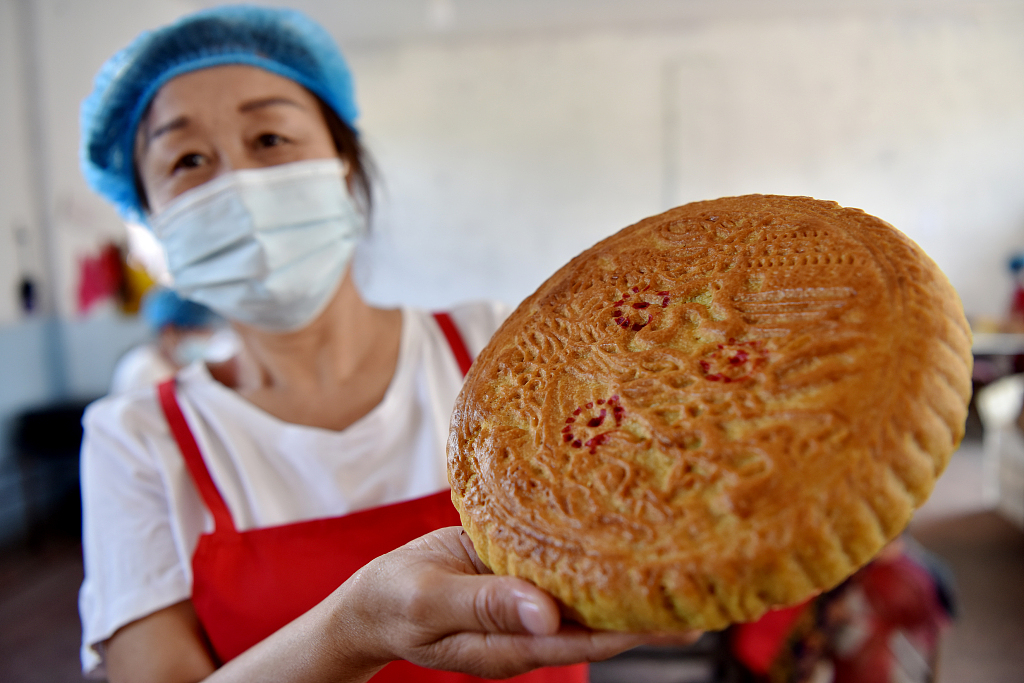 A worker shows a traditional mooncake made with flax oil at a food factory in Pangjiabao Town of Zhangjiakou, north China's Hebei Province on September 14, 2023. /CGTN