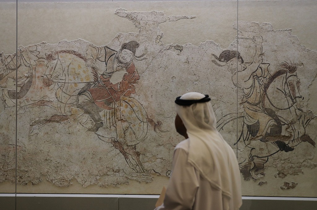 A visitor studies an ancient Chinese mural depicting polo-playing dating back to the Tang Dynasty (618-907) at an exhibition in Beijing, May 13, 2019. /CFP