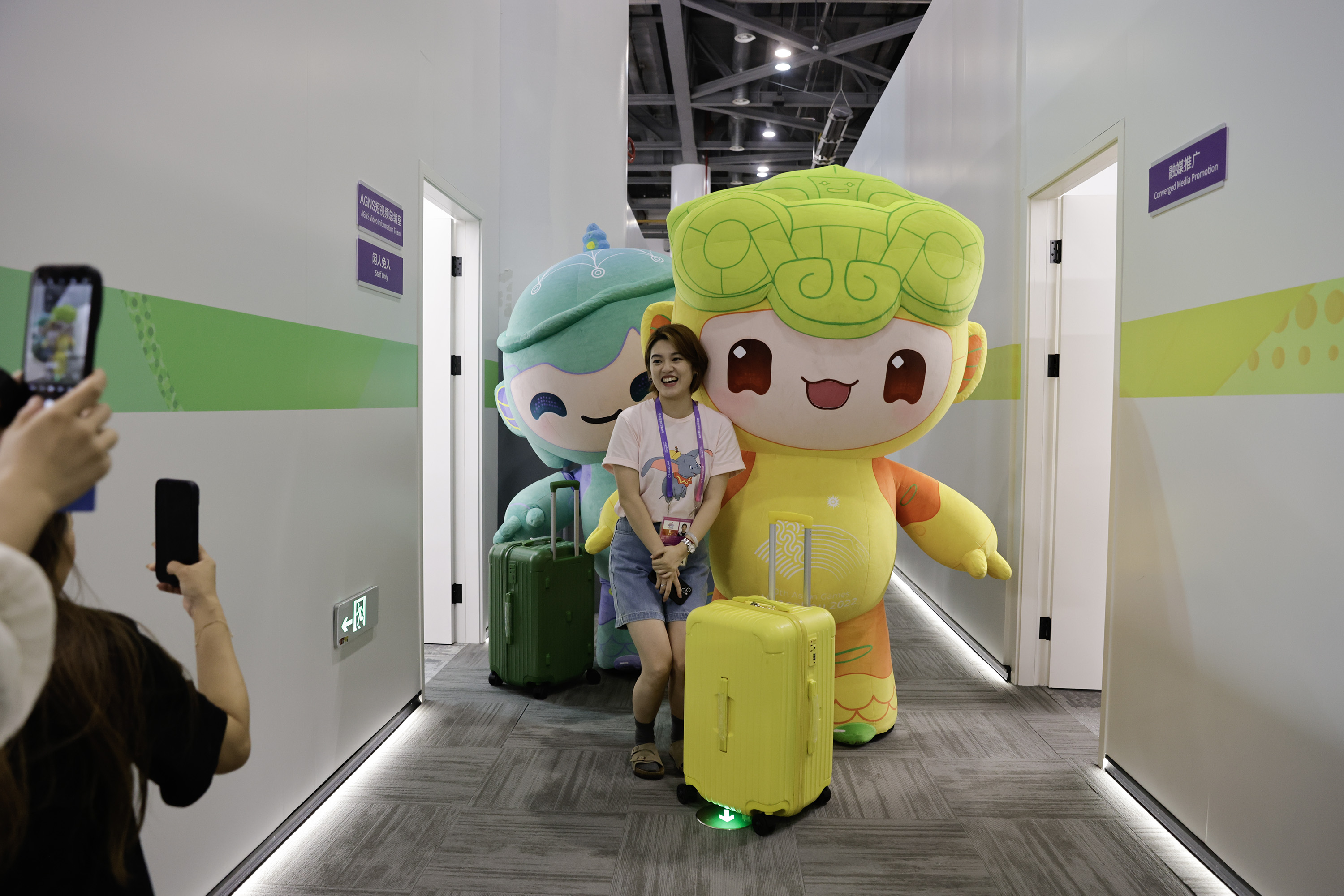 A photo shows an Asian Games staff member posing with mascots on September 19, 2023, in Hangzhou, Zhejiang. /IC