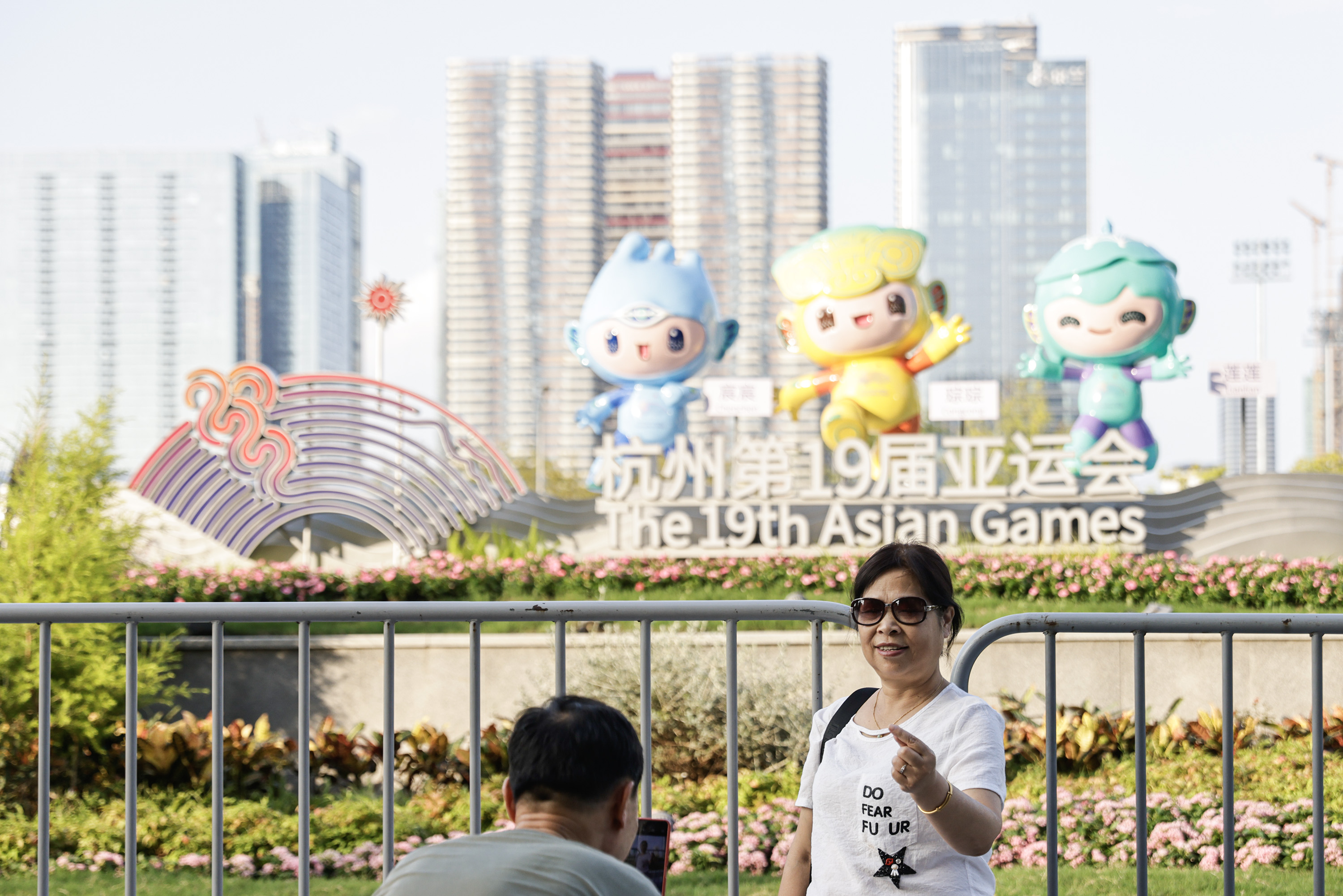 A photo shows a woman posing in front of the 19th Asian Games mascots on September 17, 2023, in Hangzhou, Zhejiang. /IC