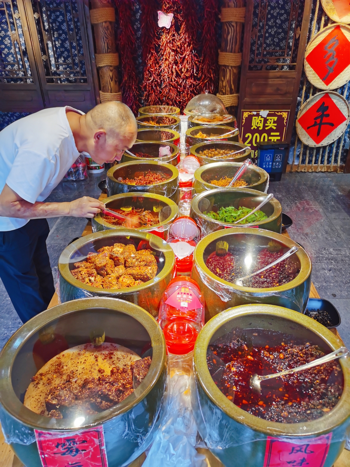 A tourist smells vegetables pickled in soy sauce at a shop in Qingyan ancient town in Guiyang, southwest China's Guizhou Province, on August 28, 2023. /CGTN