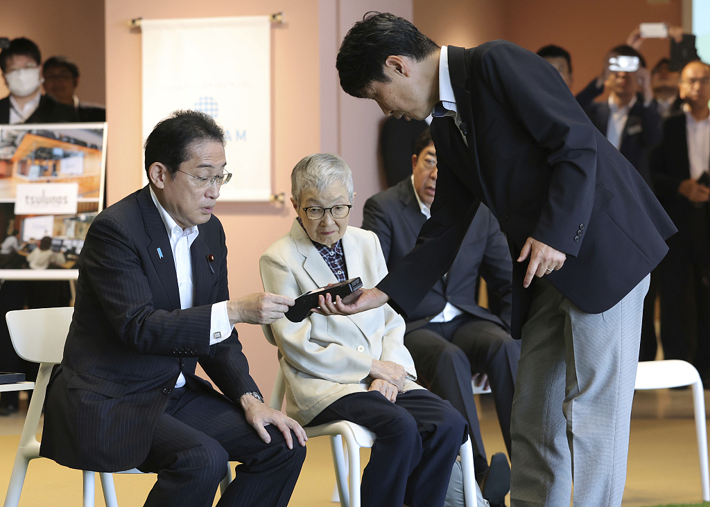 Japan's Prime Minister Fumio Kishida (L) listens to an explanation about shared taxis for the elderly and disabled persons in Maebashi City, Gunma Prefecture, on August 3, 2023. /CFP