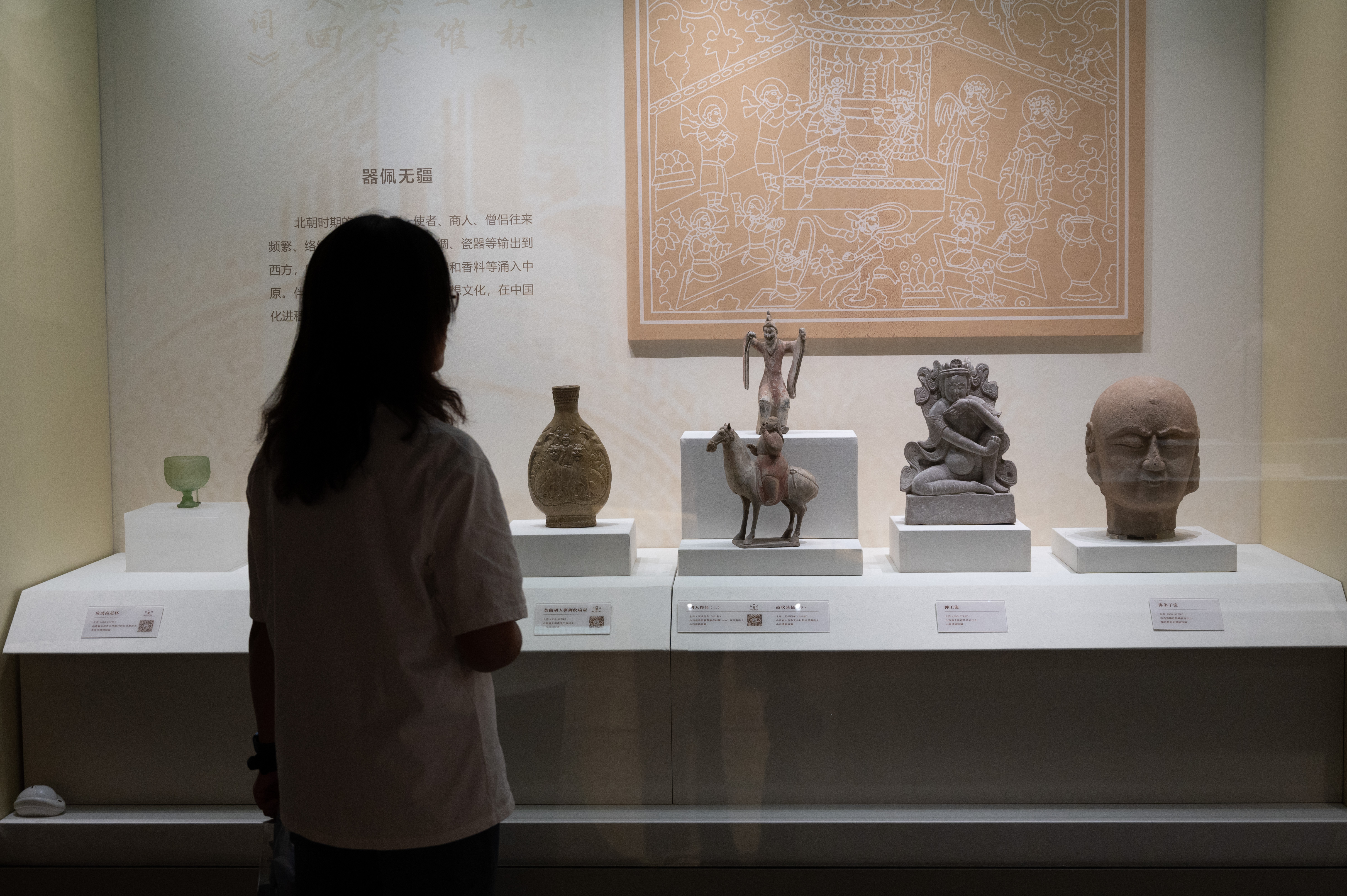 A photo taken on September 22, 2023 shows a visitor viewing cultural relics on display at Shanxi Museum as part of its newly-opened themed exhibition. /IC