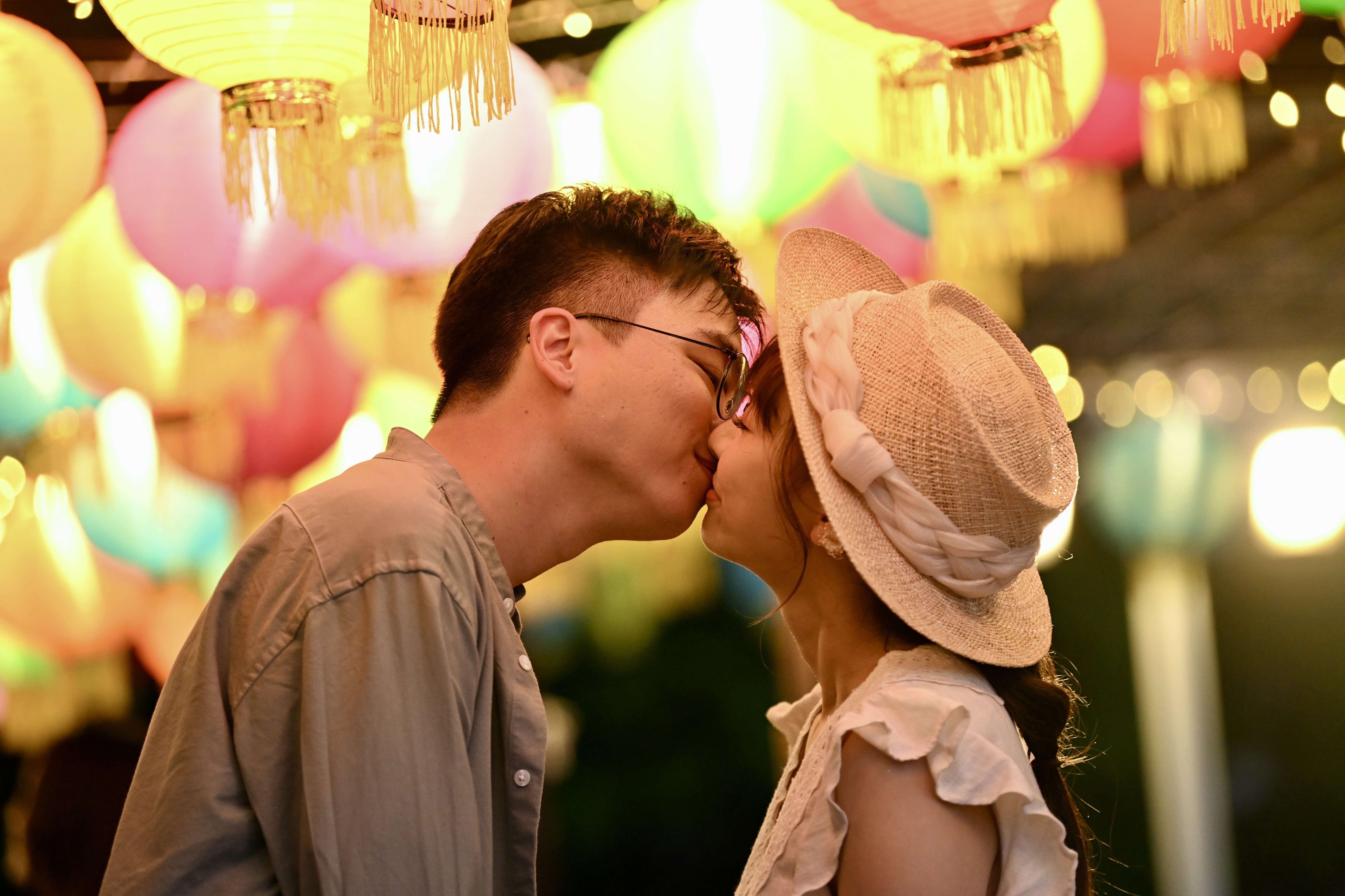 A couple steals a moment to share a kiss under lanterns strung up at the Kennedy Town promenade on September 25, 2023 in Hong Kong. /IC