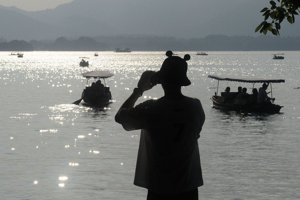 A photo shows a person taking a picture of the scenery at the West Lake on September 25, 2023 in Hangzhou, Zhejiang. /CFP
