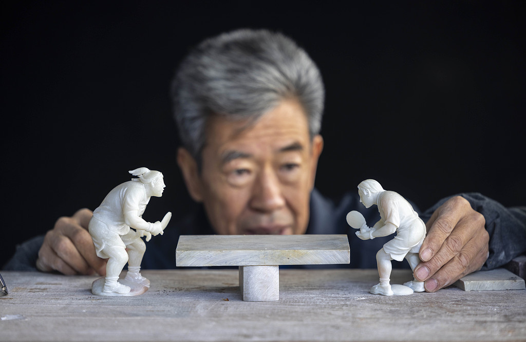 Artisan Qian Gaochao shows off his chicken-blood stone carving of a table tennis game on February 22, 2023 in Lin'an, Hangzhou. /CFP