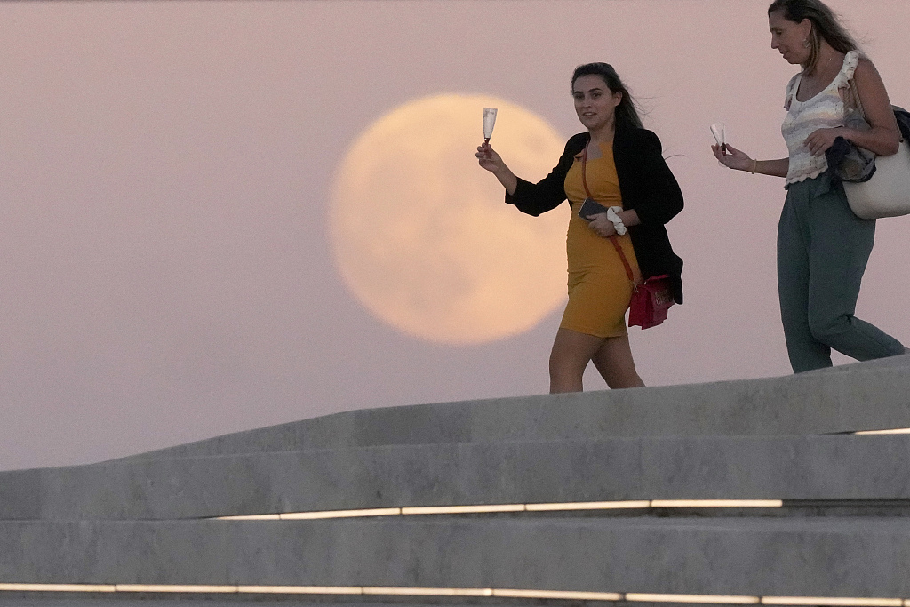 People have drinks on the roof of the Museum of Art, Architecture and Technology in Lisbon, as the full moon rises in the background on September 28, 2023. /CFP