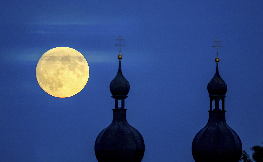 The full moon shines next to the towers of the church of St. Simon and Jude in Prague, Czech Republic on September 28, 2023. /CFP