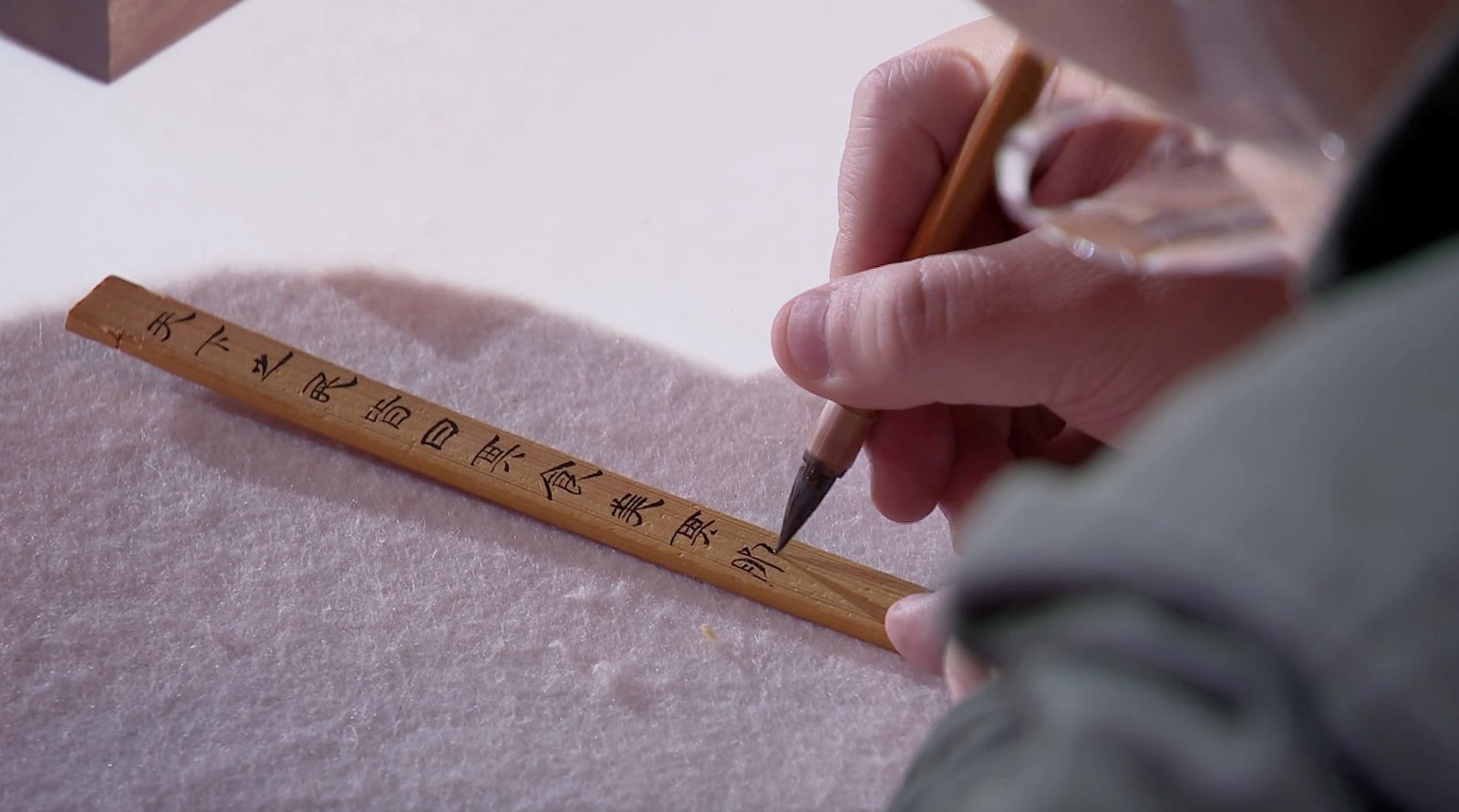 A calligraphy enthusiast writes down his hopes and goals for the future on a bamboo slip in clerical script. /CGTN