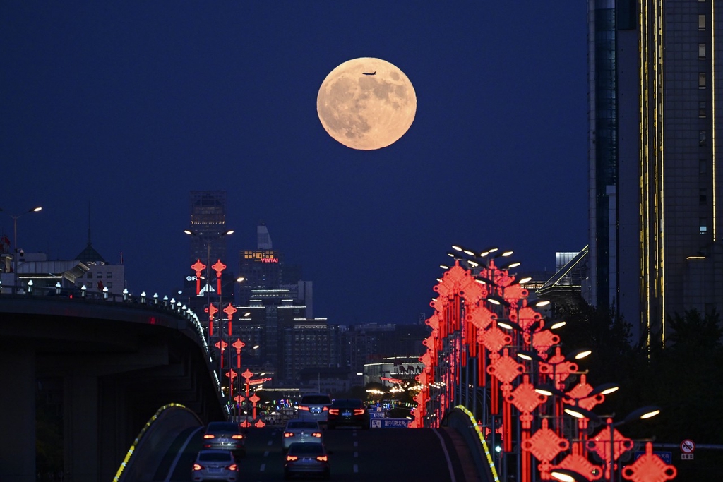 A photo taken on September 29, 2023, shows an airplane flying across a view of the full moon above Chang’an Avenue in Beijing. /IC