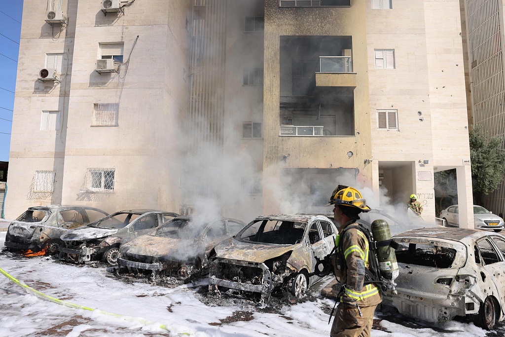 Israeli fire brigade teams douse the blaze in a parking lot outside a residential building following a rocket attack from Gaza in the southern Israeli city of Ashkelon, October 7, 2023. /CFP