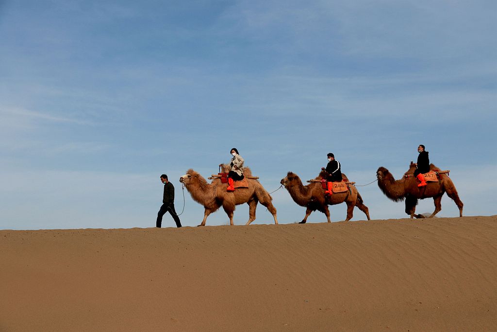 File photo shows tourists riding camels in Jiuquan, Gansu. /CFP
