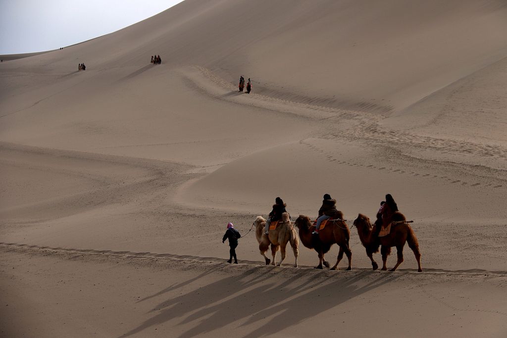 File photo shows tourists riding camels in Jiuquan, Gansu. /CFP