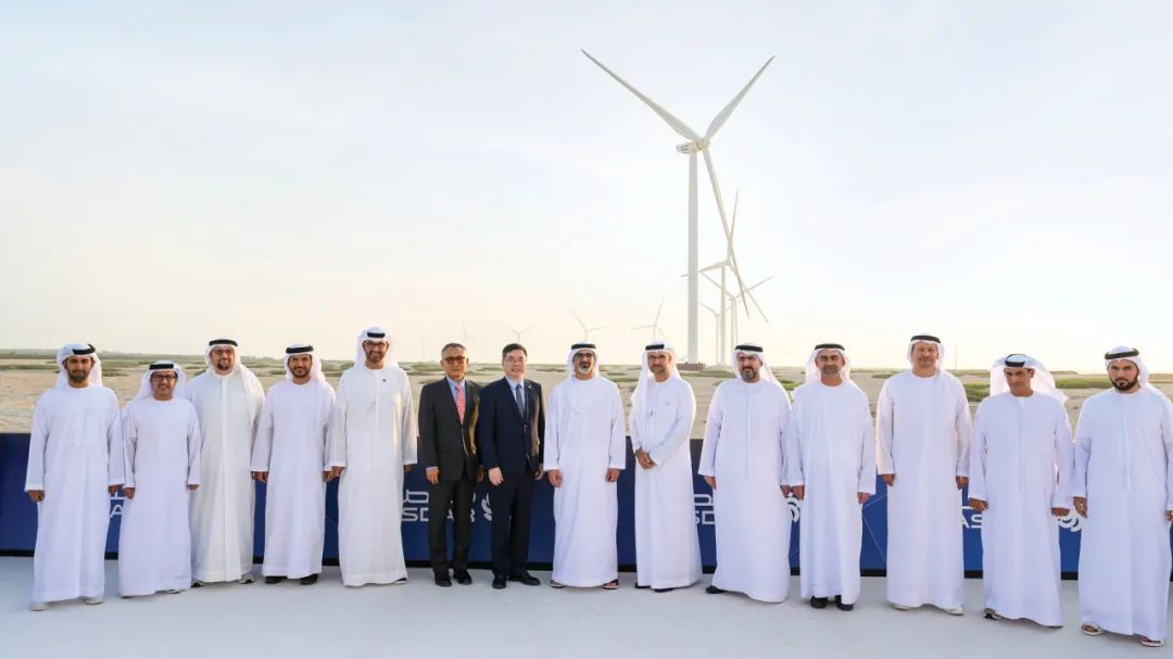 Group photo of personnel from China and UAE standing in front of the wind power project built in Abu Dhabi, UAE, September 2023. /PowerChina