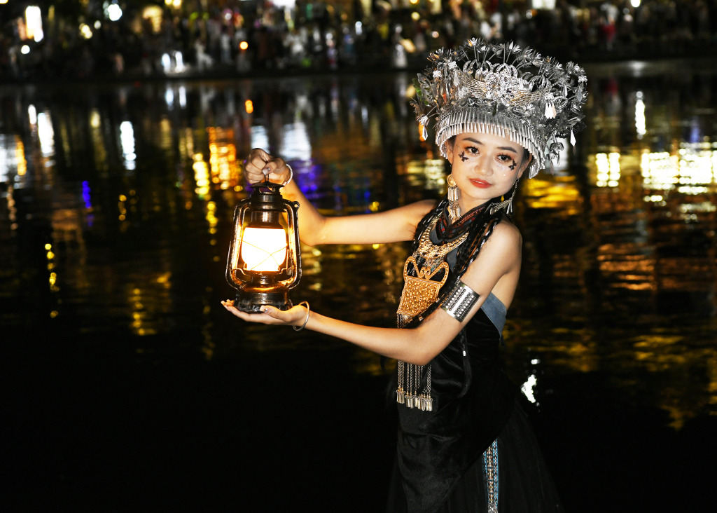 A tourist dressed in folk costume poses for a photo in Fenghuang County, central China's Hunan Province, August 7, 2023. /CFP