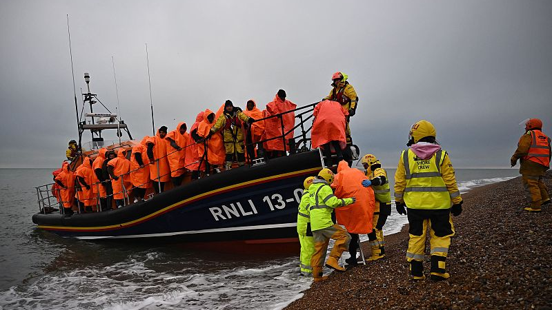 Migrants, picked up at sea attempting to cross the English Channel, are helped ashore from an Royal National Lifeboat Institution lifeboat, at Dungeness on the southeast coast of England, December 9, 2022. /CFP