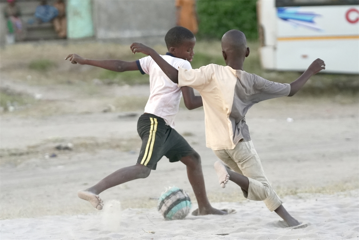 Barefooted youngsters enjoy a game of football despite the lack of a proper playing field or ball at a small village in Tanzania. /CGTN