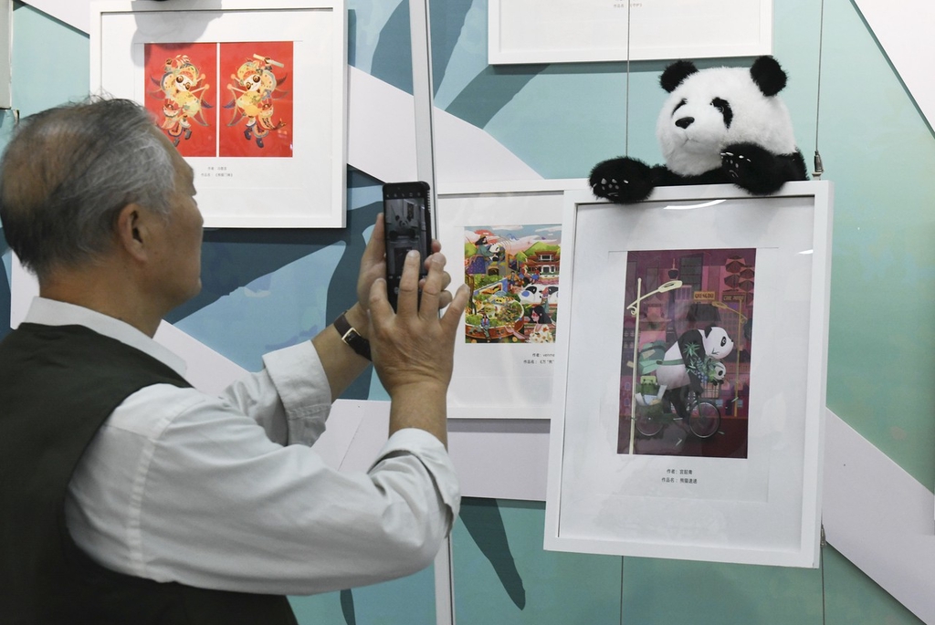 A photo taken on October 8, 2023 shows visitors taking photos with panda-themed illustrations at the exhibition in Chongqing, China. /CFP