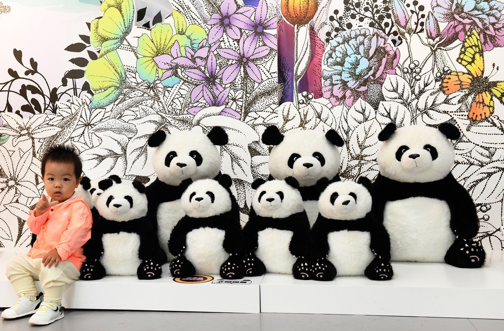 A photo taken on October 8, 2023 shows visitors taking photos with stuffed pandas displayed at the illustration exhibition in Chongqing, China. /CFP