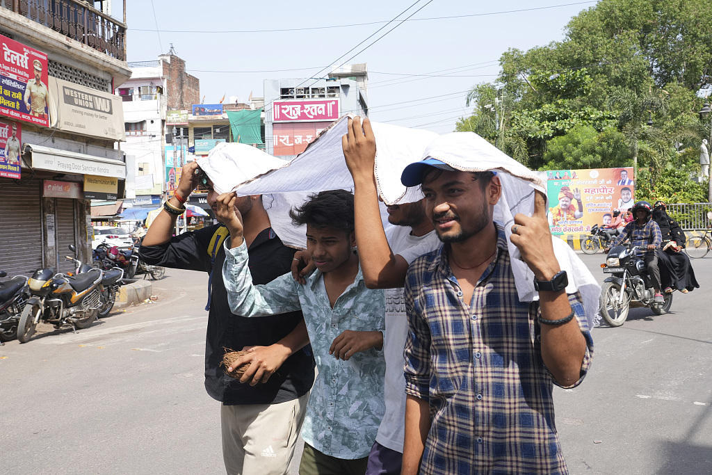 Pedestrians share a piece of cloth to protect themselves from the sun on a hot summer day in Prayagraj, India, May 21, 2023. /CFP