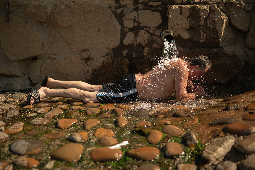 Cooling himself under a water outlet in the Minho River during a heatwave in Ourense, Spain, August 8, 2023. /CFP