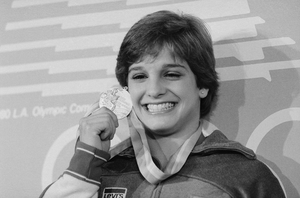 Mary Lou Retton of the U.S. holds up her gold medal at the 1984 Los Angeles Olympic Games. /CFP