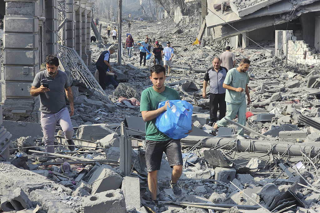 Palestinians walk through the rubble of buildings destroyed by Israeli airstrikes in Gaza, October 10, 2023. /CFP