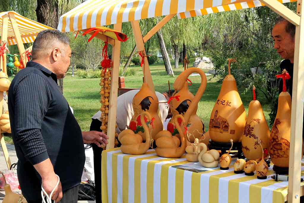 A visitor looks at pyrography gourd products at the Autumn Yellow River Fair in Ji'nan, Shandong Province, on October 11, 2023. /CFP