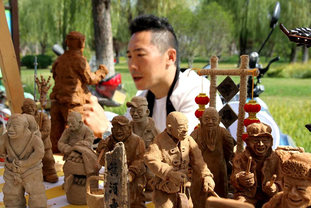 Li Zhiguo is making clay figurines at the Autumn Yellow River Fair in Ji'nan, Shandong Province, on October 11, 2023. /CFP